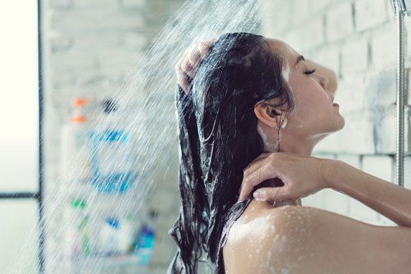 シャワーで髪を流す女性