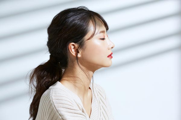 室内に降り注ぐ日差しを浴びる女性