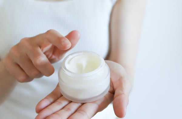 スキンケアクリームを手に持つ女性