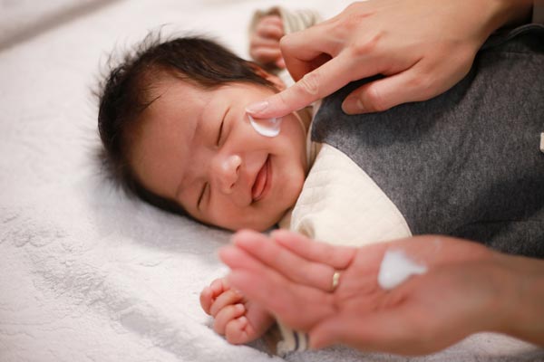 赤ちゃんの顔にクリームを塗る