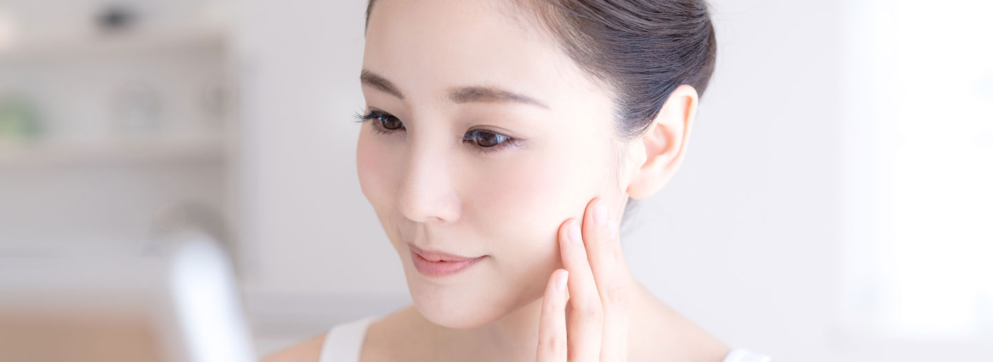 鏡で肌を見る女性