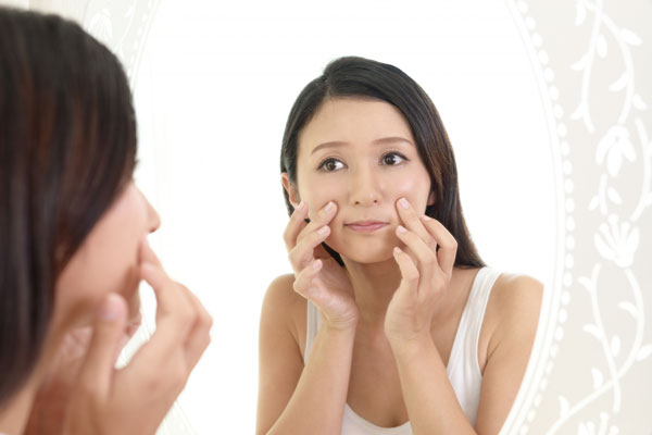 鏡で肌をチェックする女性