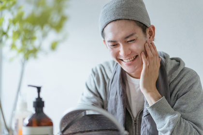 笑顔で鏡で自分の肌を見る男性