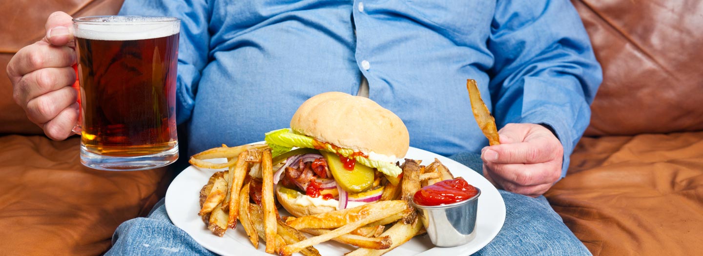 ジャンクフードを食べる太った男性