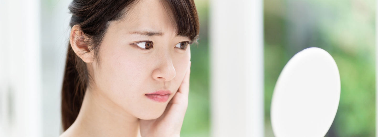 困った顔で鏡を見る女性