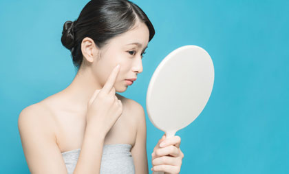 鏡で肌をチェックする女性