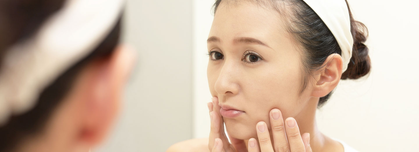 鏡で肌をチェックする女性