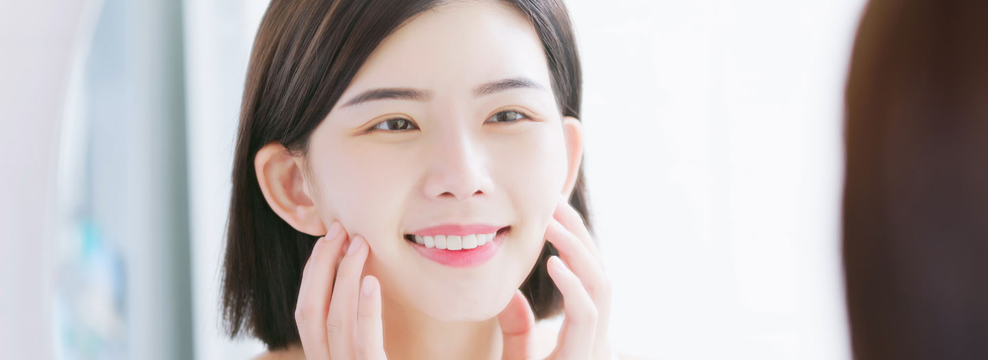 鏡で肌を見る女性