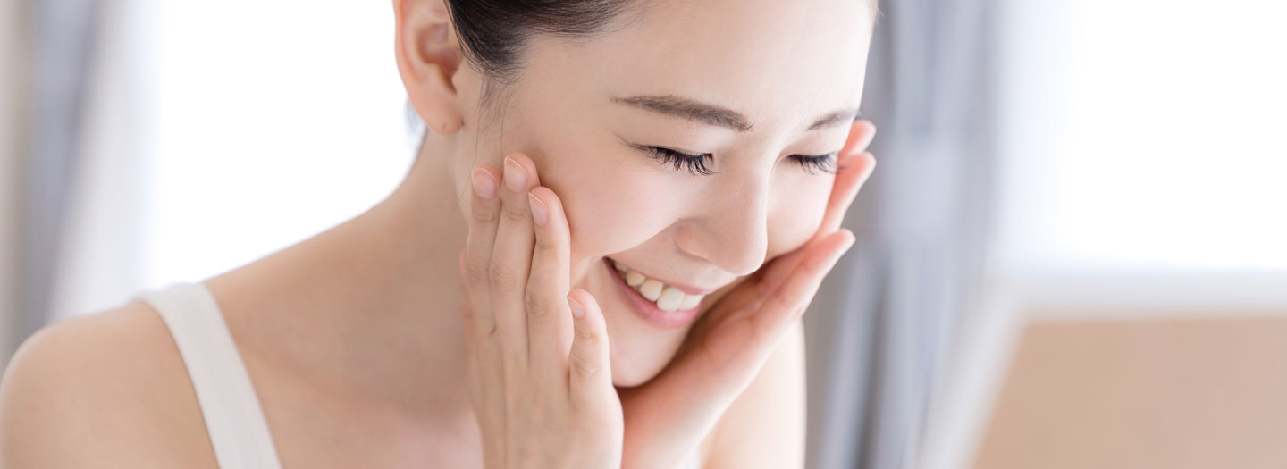 鏡を見ながら笑顔でスキンケアする女性