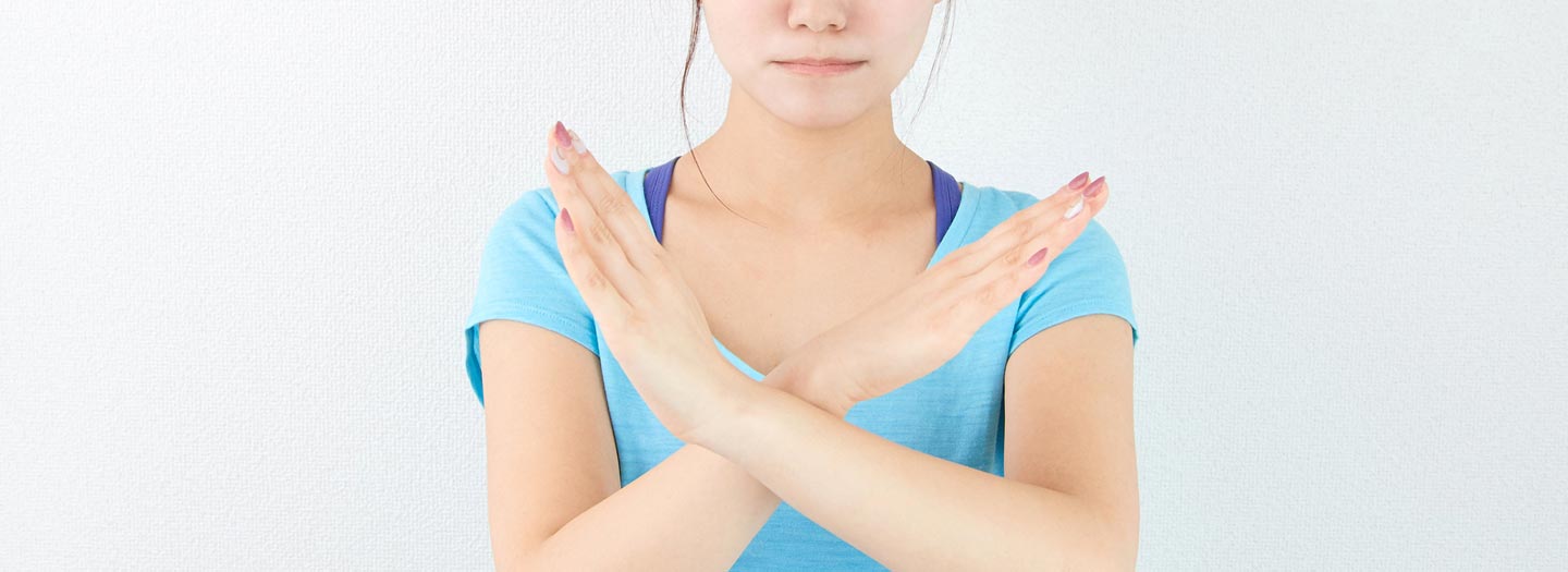 腕で×印をつくる女性
