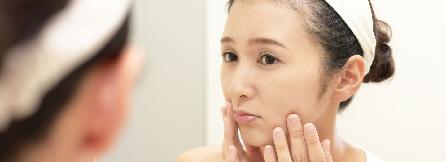 困った顔で鏡を見る女性