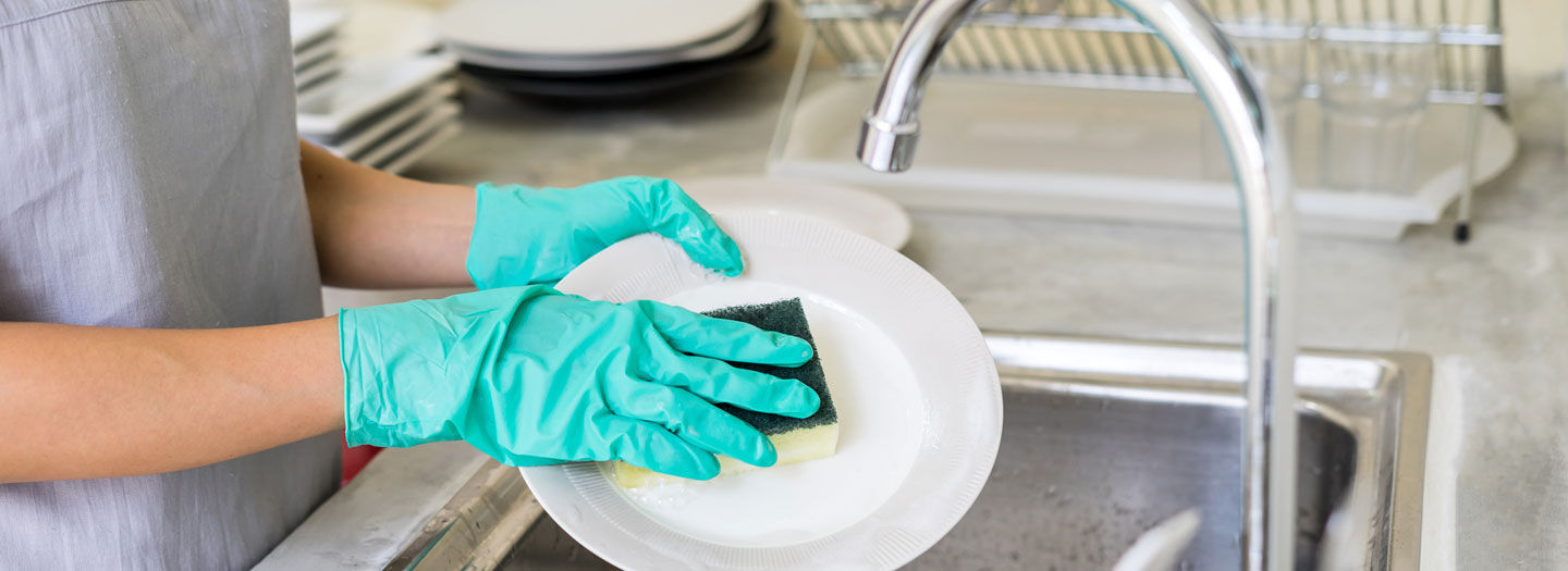 ゴム手袋をしながら食器を洗う人