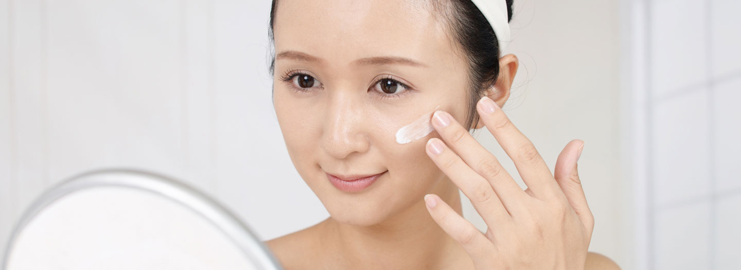 スキンケアで顔にクリームを塗る女性