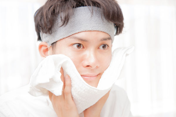 洗顔後にタオルで顔を拭く男性