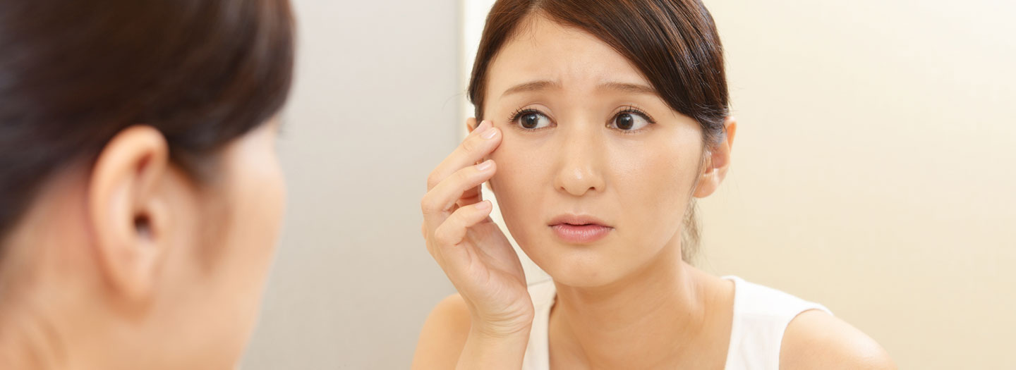 肌荒れを鏡で確認する女性