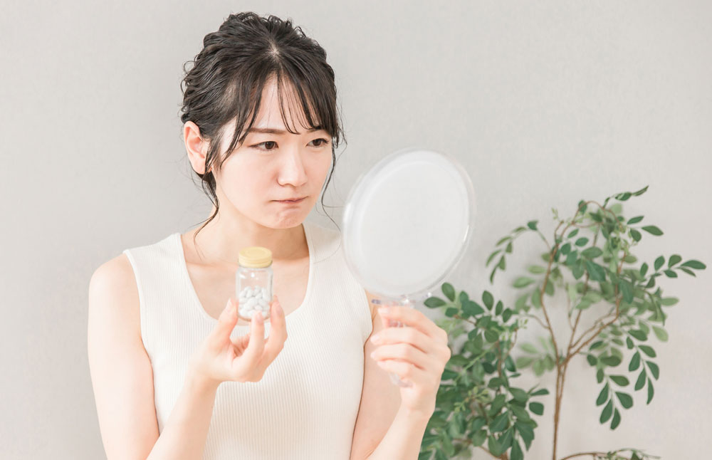 肌荒れに悩みサプリメントを持つ女性