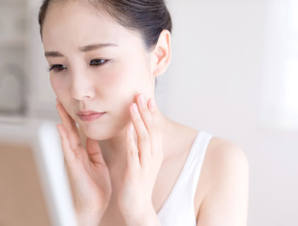 肌トラブルのある女性が鏡を見る