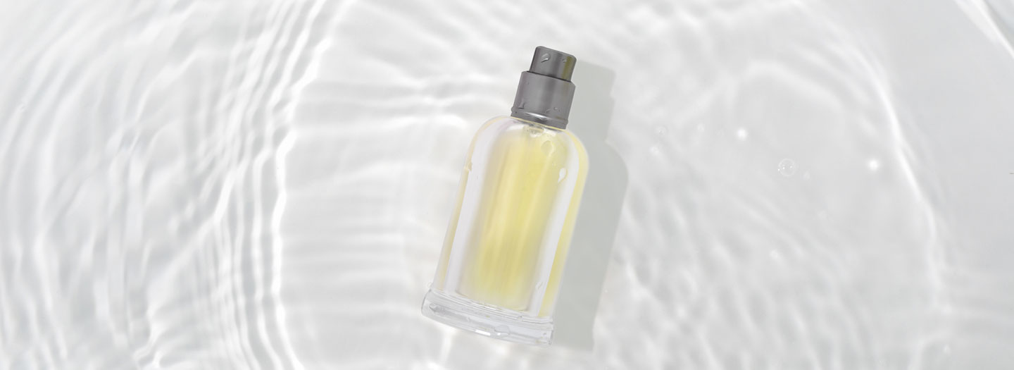 白い背景に円が付いた水面に化粧品の香水瓶