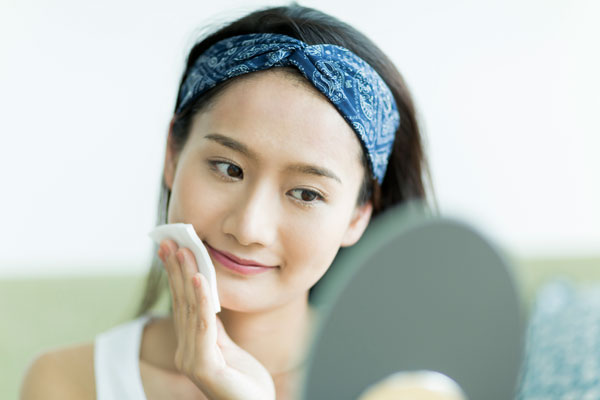 クレンジングローションでメイクを拭き取る女性