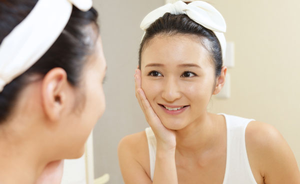 鏡を見ながらスキンケアする女性