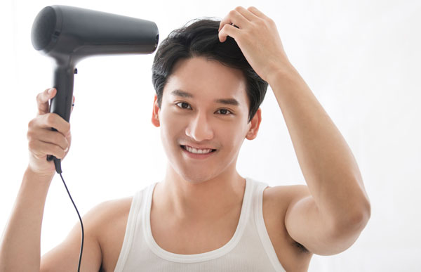 ドライヤーで髪を乾かす男性